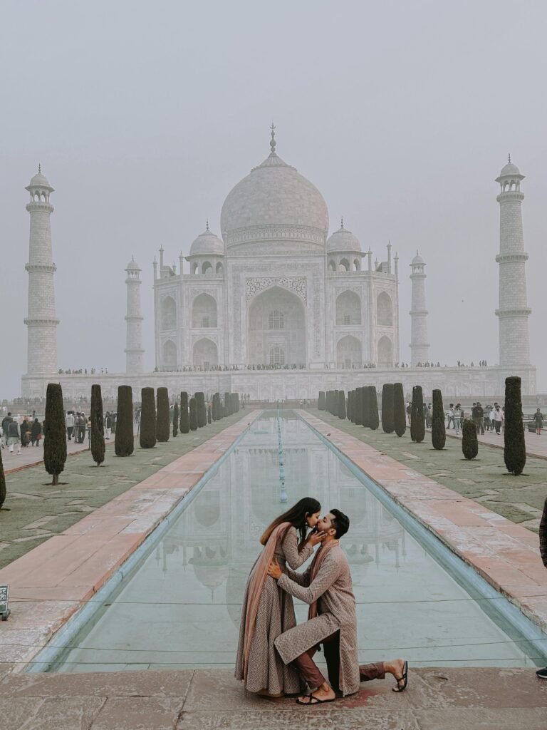 A romantic couple kissing in front of the iconic Taj Mahal in Agra, India.