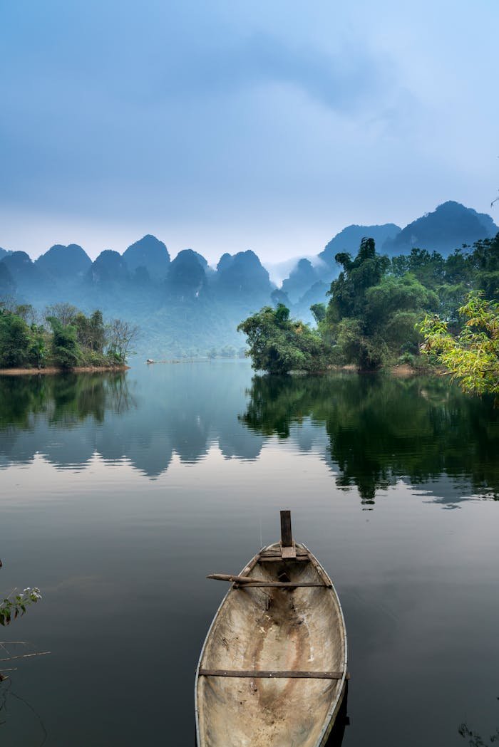 A tranquil river scene with a canoe, misty mountains, and lush greenery, perfect for nature lovers.