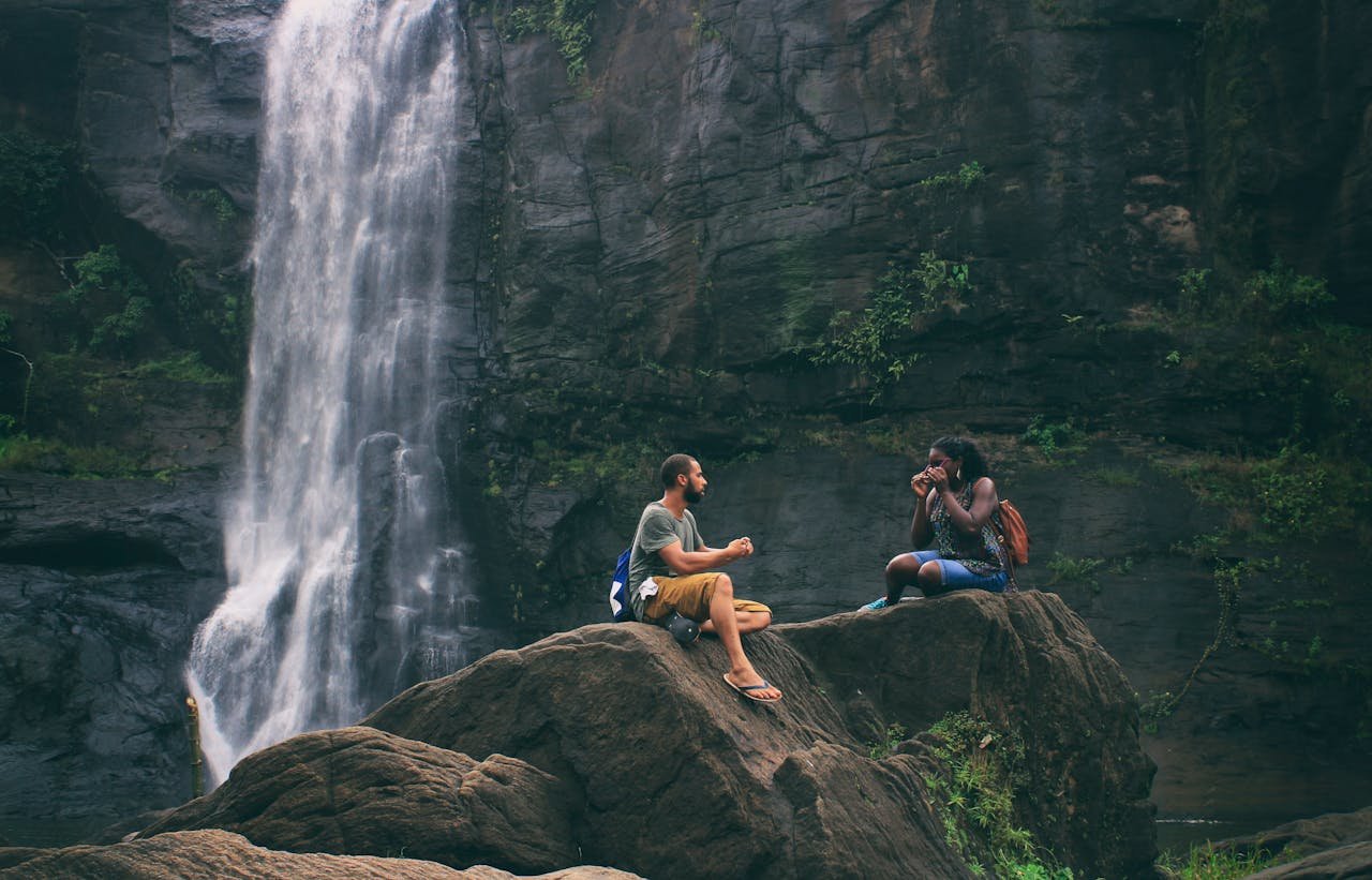 A serene moment captured by a waterfall in India with a couple enjoying nature's beauty together.