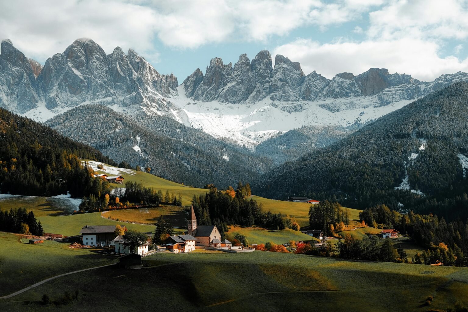 A breathtaking view of a rural village set against dramatic mountains in autumn.